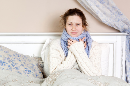 Malaltia amb dolor de gola terrible. Imatge de primer pla d'una dona jove amb el nas vermell al llit amb un mocador gruixut i tocant el coll i el cap sentint dolor